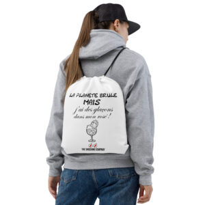 Sac à cordons blanc avec design noir montrant la phrase « La planète brûle mais j’ai des glaçons dans mon rosé ! » et une planète en flammes dans un verre.