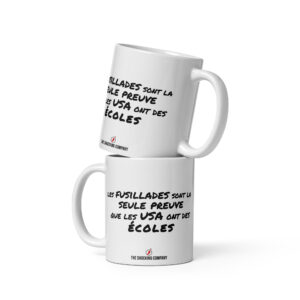 Tasse blanche portant la phrase « Les fusillades sont la seule preuve que les USA ont des écoles », satire politique américaine à l’humour noir.