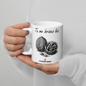 Tasse blanche humoristique avec la phrase « Tu me brises les » en écriture manuscrite et deux noix, dont une brisée.