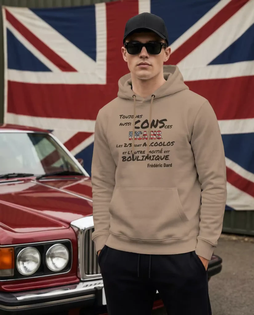 Sweat à capuche beige imprimé d'une citation moqueuse sur les Américains, porté devant un drapeau britannique