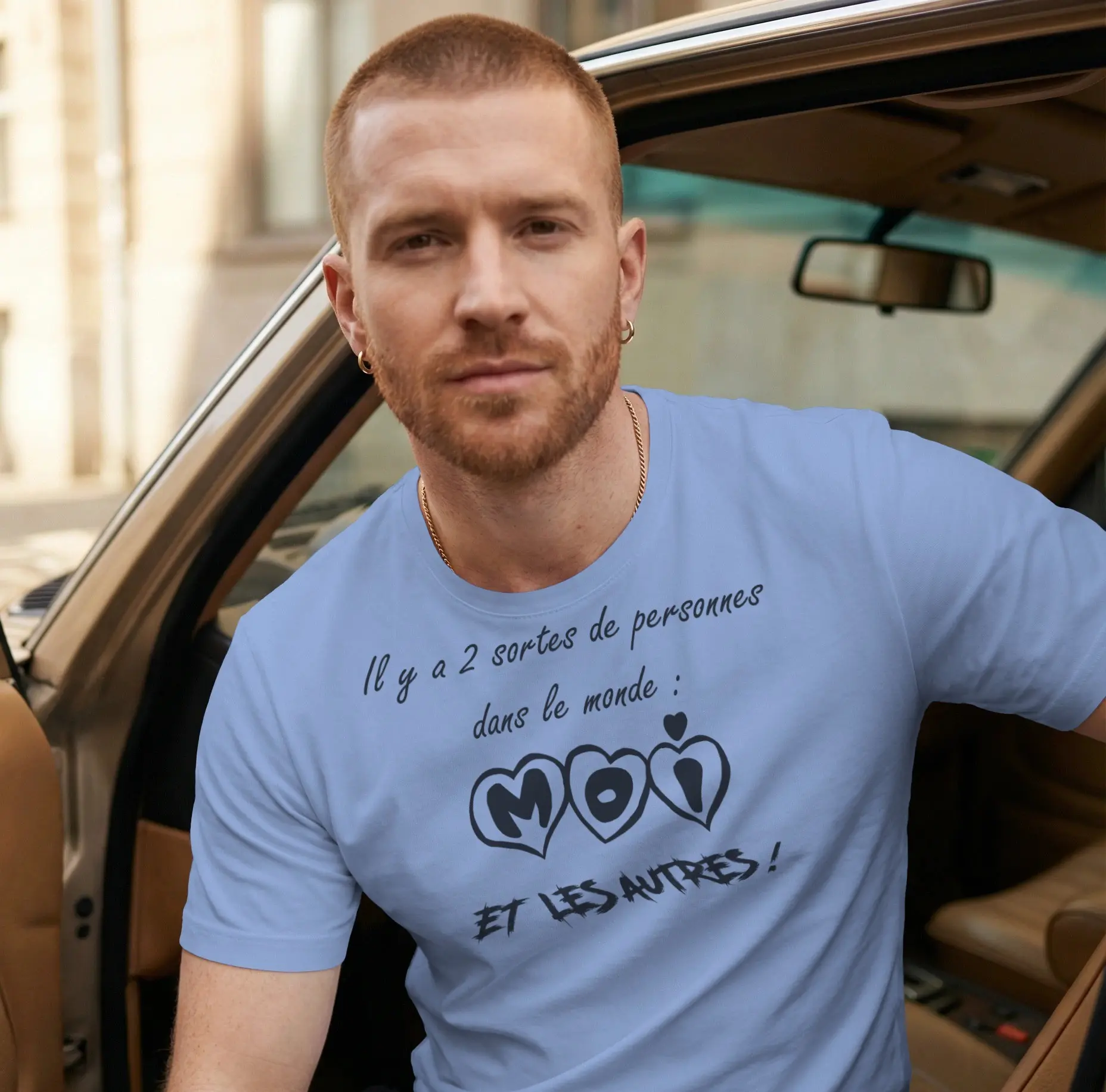 Homme portant un tee-shirt bleu ciel avec l'inscription "Il y a 2 sortes de personnes dans le monde : MOI et les autres !" écrite en lettres capitales dans des cœurs