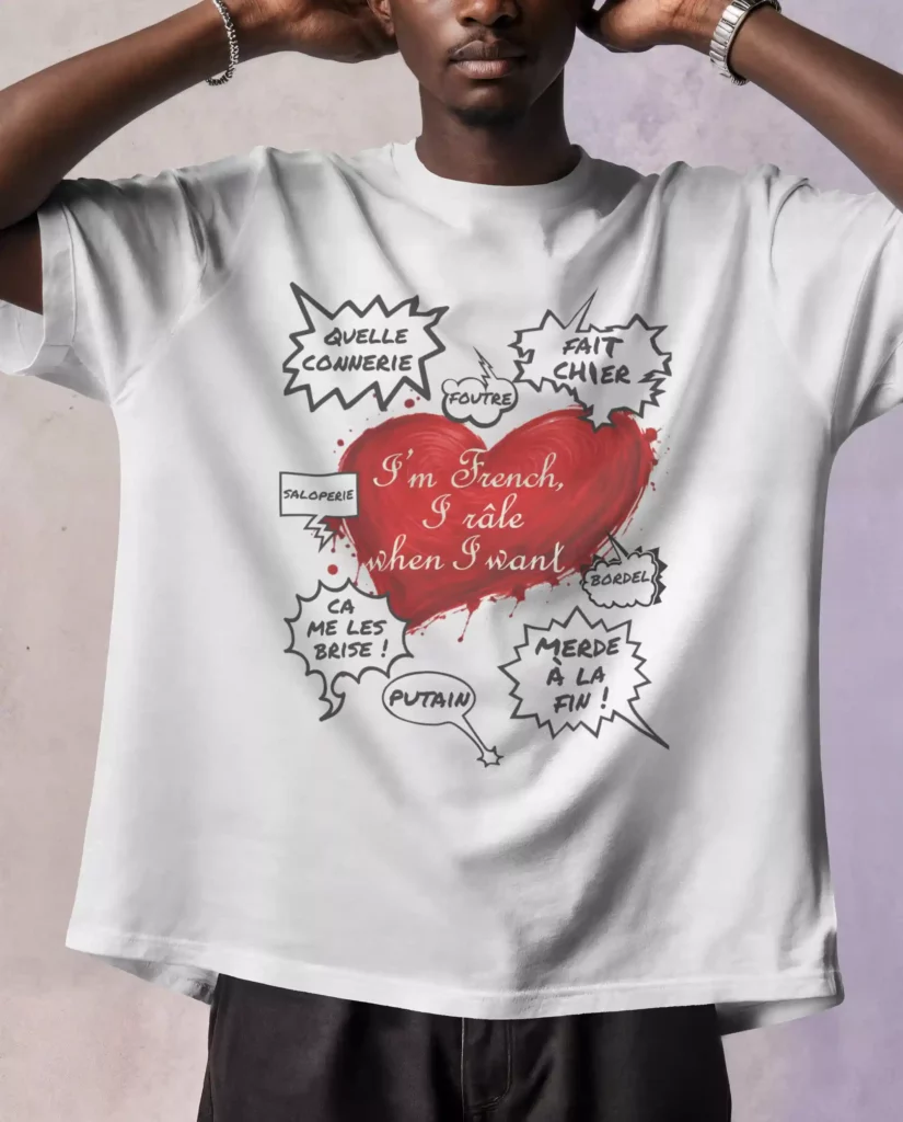 T-shirt blanc imprimé d'un cœur rouge « I'm French, I râle when I want » entouré de bulles de BD remplies de jurons français