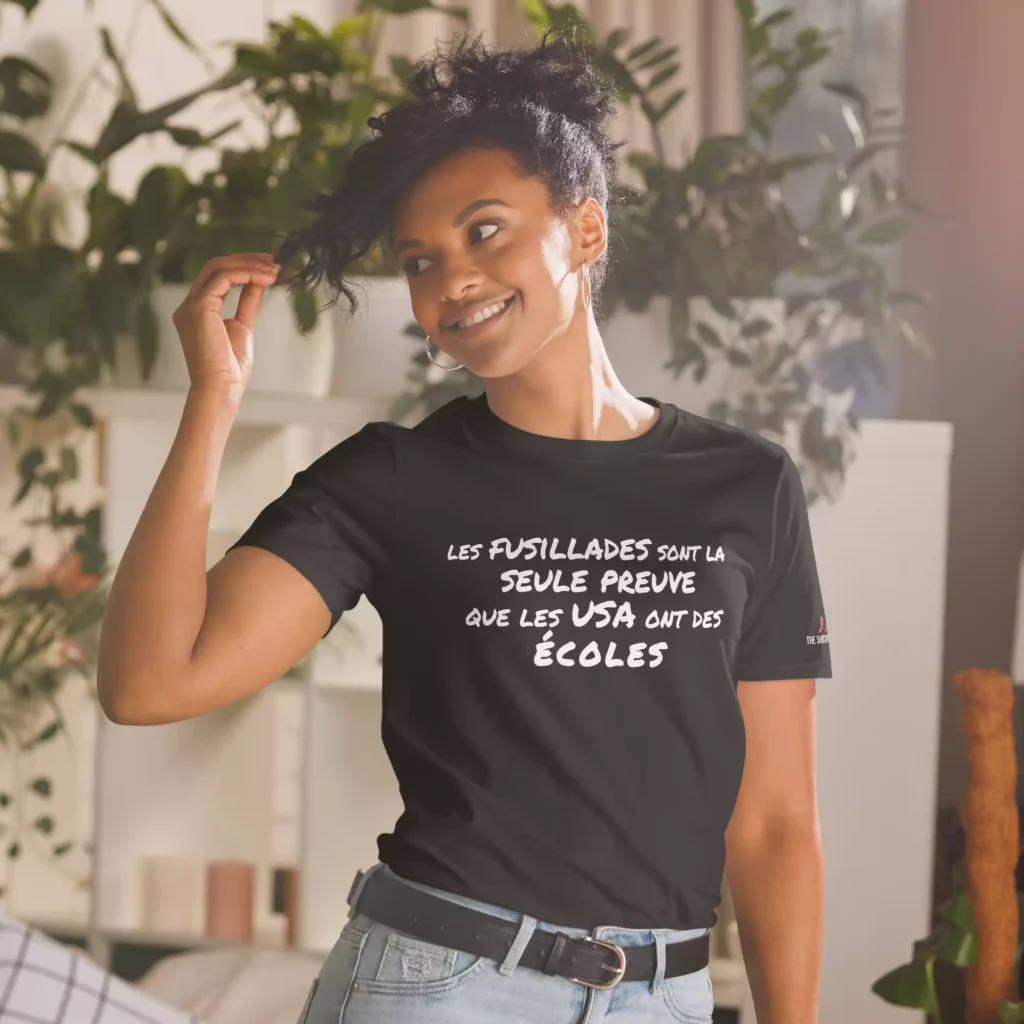 T-shirt noir porté par une femme, imprimé du slogan blanc « Les fusillades sont la seule preuve que les USA ont des écoles »